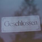 Ein 25-Euro-Geschenkgutschein mit weihnachtlichem Design, umgeben von Tannenzweigen und einer Sparbüchse, als Tipp für falschfreie Geschenke.
